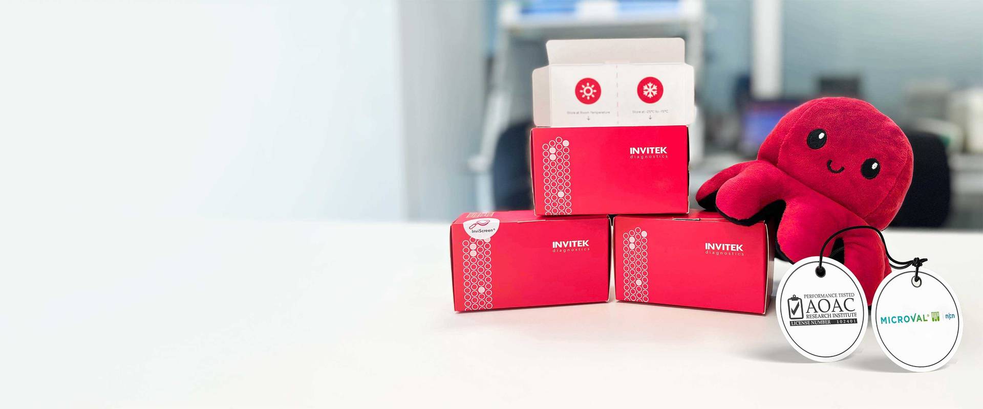 Three red boxes containing qPCR reagents for Salmonella ssp detection from Food Matrices. The boxes are labelled with MicroVal and AOAC certifications and equivalence methods. There is also a red  octopus alongside the kits, this is the Brand Mascot 