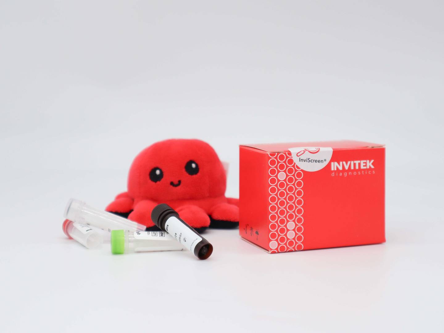 InviScreen Mycoplasma kit: plush red octopus “Invi” sits on a red INVITEK box; four reagent vials (red, grey, brown, green caps) stand in front.
