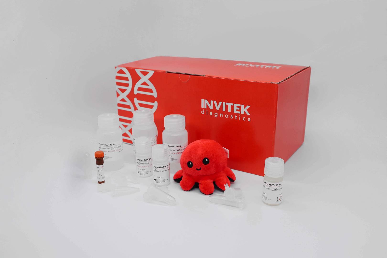 Red Invitek Diagnostics InviSorb Spin Blood Mini Kit box behind reagent bottles, reagent tubes, and spin columns.