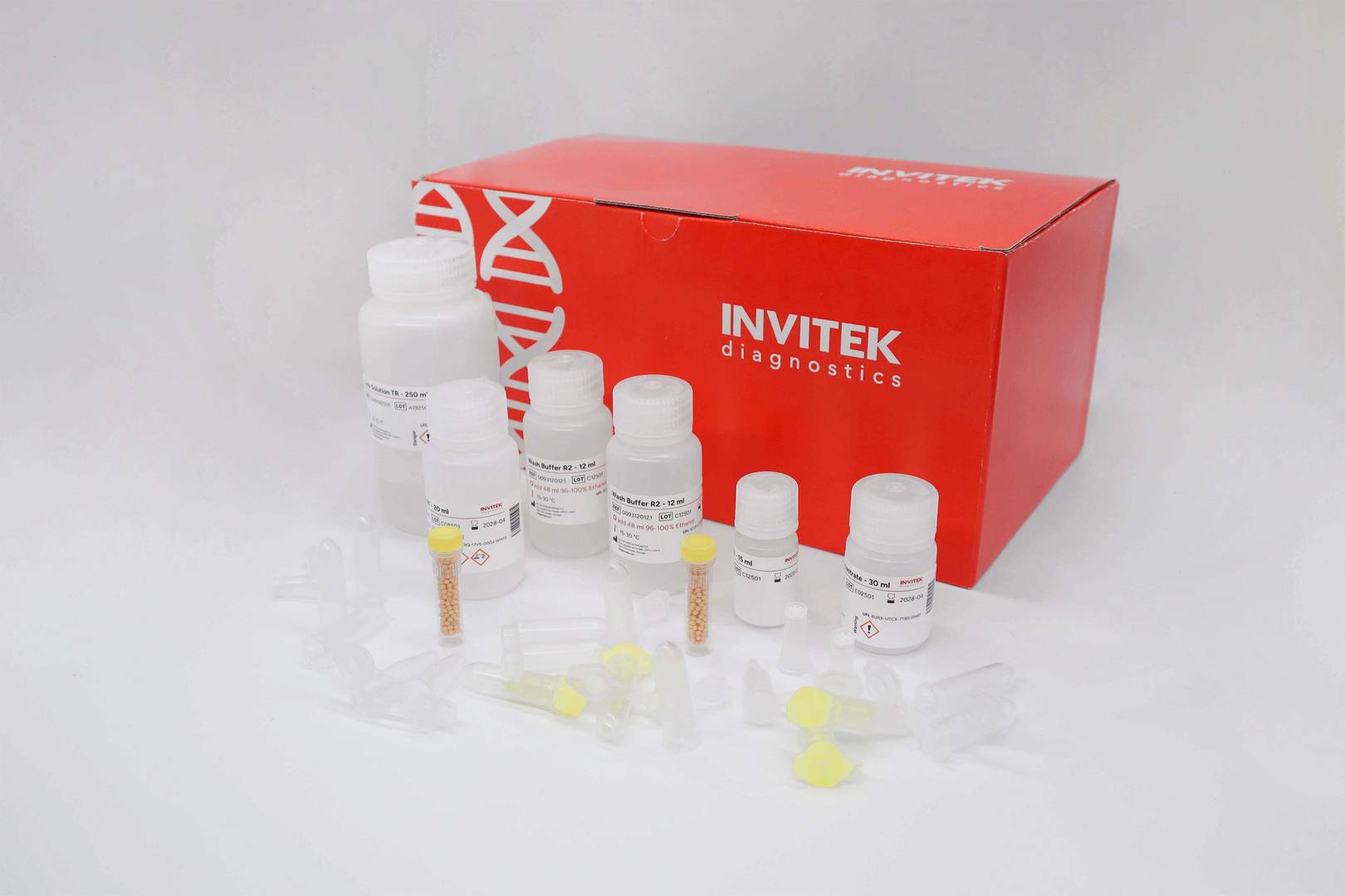 Red Invitek Diagnostics InviTrap Spin Universal RNA Mini Kit box behind reagent bottles, and color-coded reagent vials with yellow spin filters, and tubes laying scattered in front.