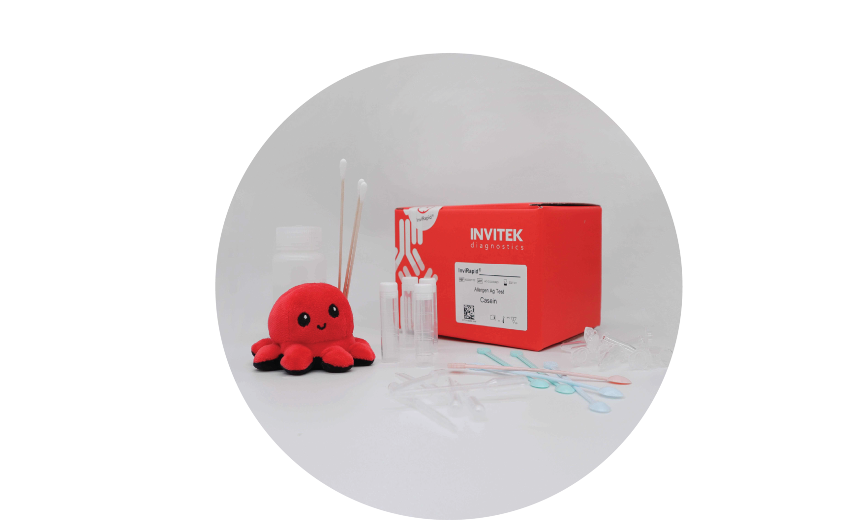 Red Invitek Diagnostics InviRapid Casein Allergen Ag Test box behind sample tubes next to swabs and a buffer bottle with scoops, droppers and tubes laying scattered in front.