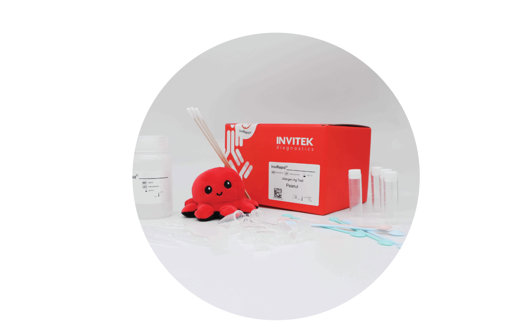 Red Invitek Diagnostics InviRapid Peanut Allergen Ag Test box behind sample tubes and swabs next to a buffer bottle with scoops, droppers and tubes laying scattered in front.