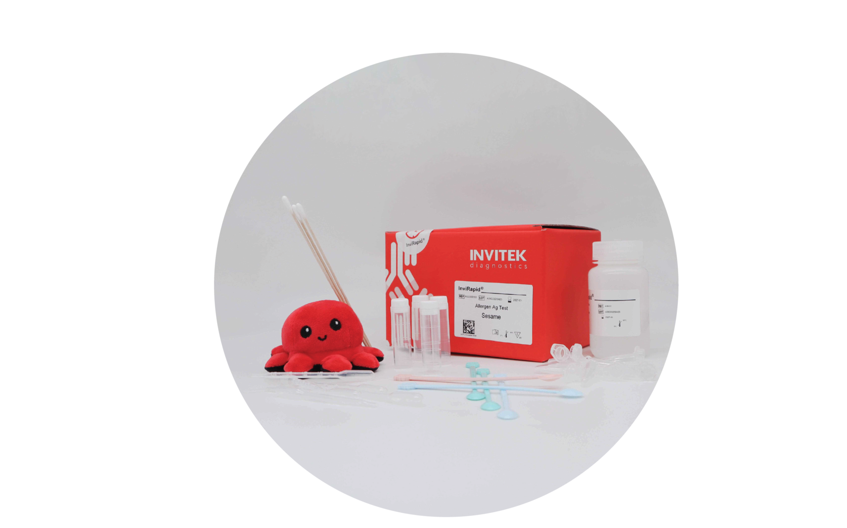 Red Invitek Diagnostics InviRapid Sesame Allergen Ag Test box behind a buffer bottle and sample tubes next to swabs with scoops, droppers and tubes laying scattered in front.