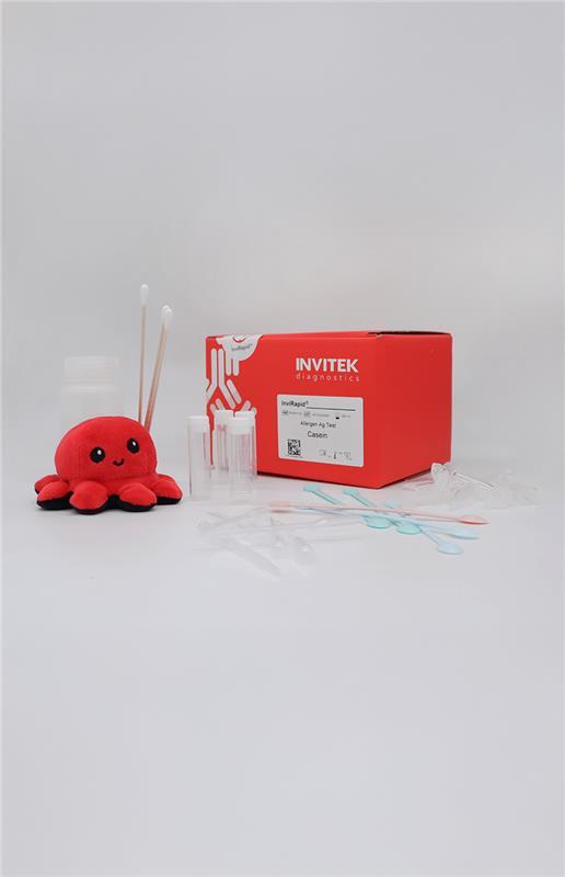 Red Invitek Diagnostics InviRapid Allergen Ag Test box behind a buffer bottle, swabs, and sample tubes with scoops, droppers and tubes laying scattered in front.